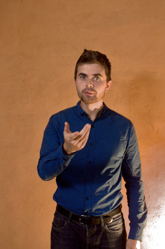 Un homme (Étienne Dupont), habillé d'une chemise bleu, tête nue, parle une main en avant.